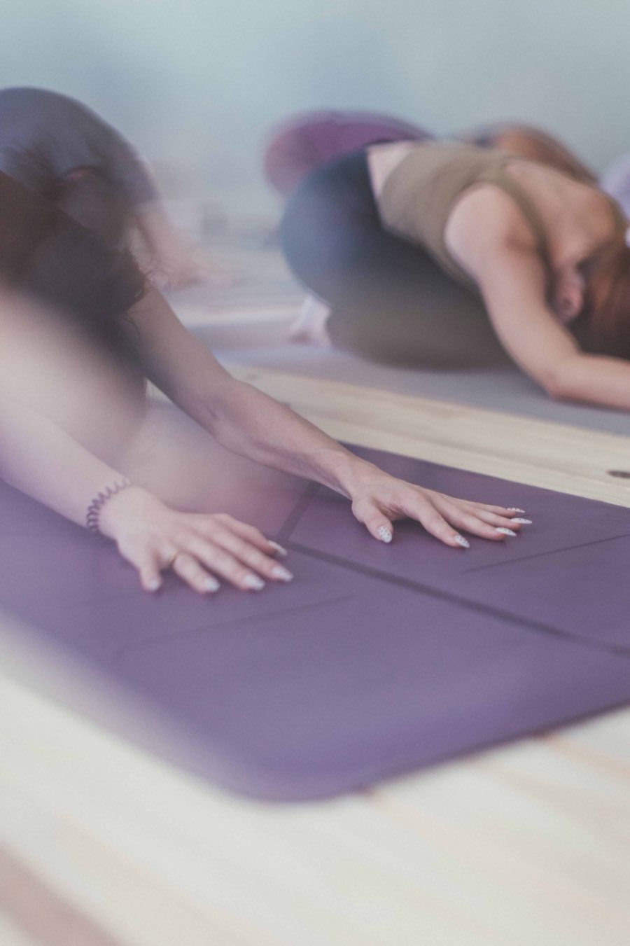 Hands resting forward on a purple mat in child&rsquo;s pose