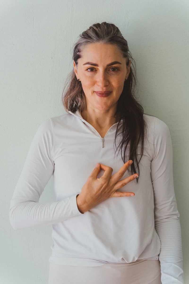 A MyZen teacher in white, one hand held in a mudra at her heart