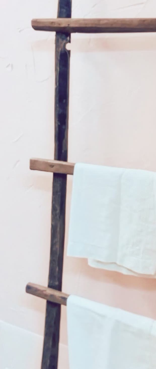 A weathered wooden ladder hung with white towels