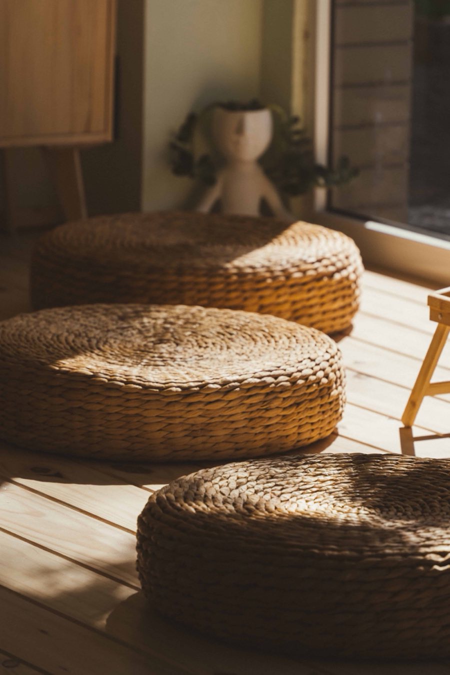 Woven floor cushions in the afternoon sun on the studio&rsquo;s wooden floor