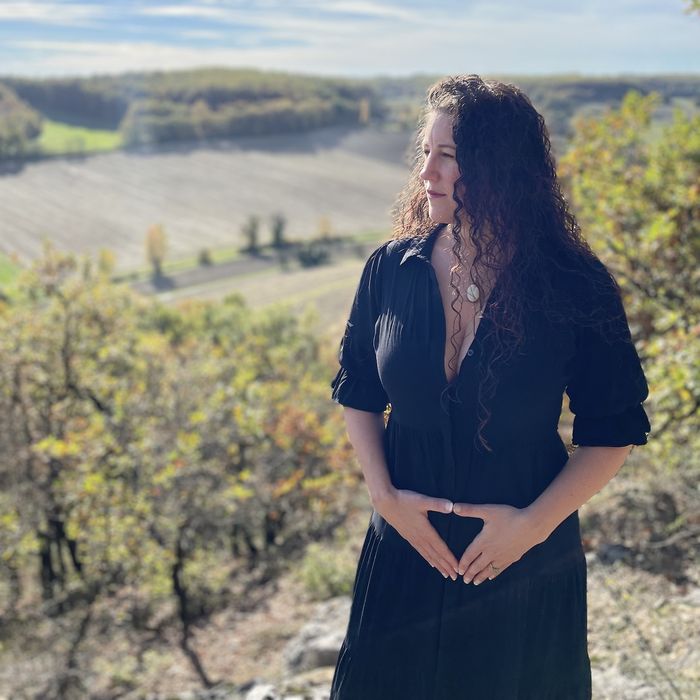 Olivia standing on a hillside, hands resting over her womb